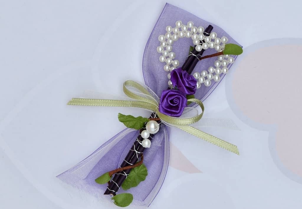 Hochzeitsanstecker - Büscherl: "Stäbe mit Perlenherz und Rosen in Lila gehalten".  Jetzt in unserem Hochzeits Onlineshop kaufen.